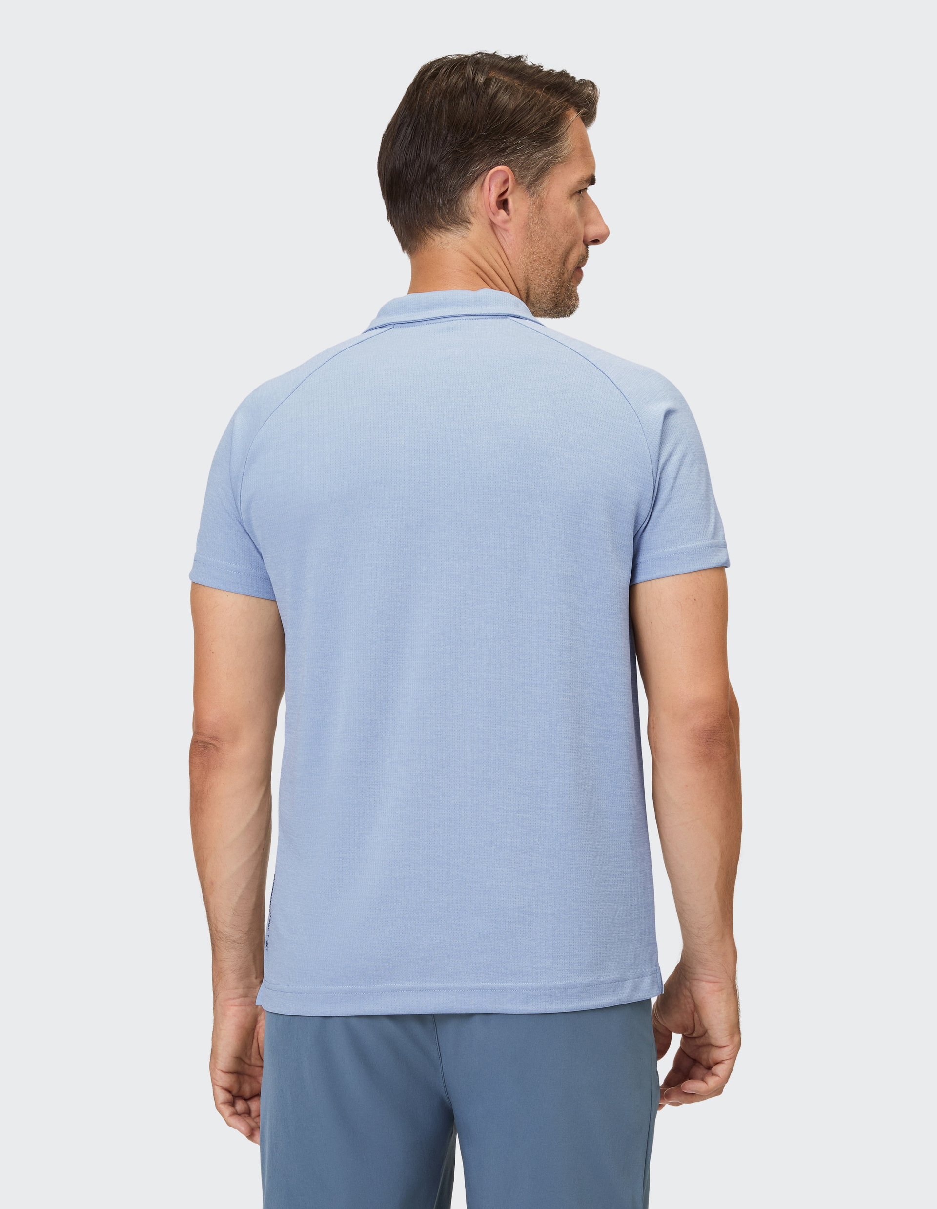 Mann trägt ein hellblaues Poloshirt mit kurzem Arm und einer dezenten Wabenstruktur.