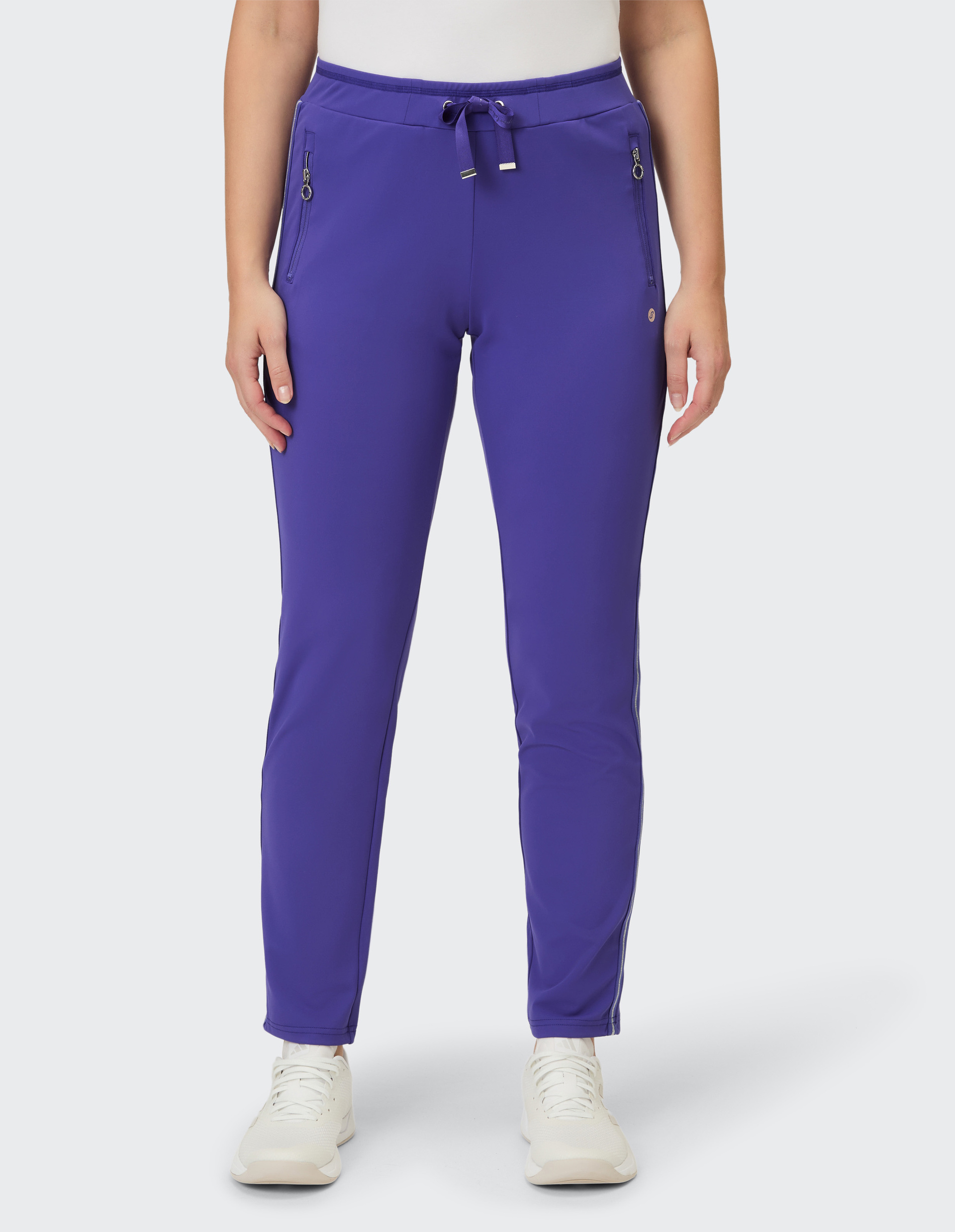 Eine Frau trägt eine lila Jogginghose mit Zierspitzendetaillierung an den Taschen und dem Bein.