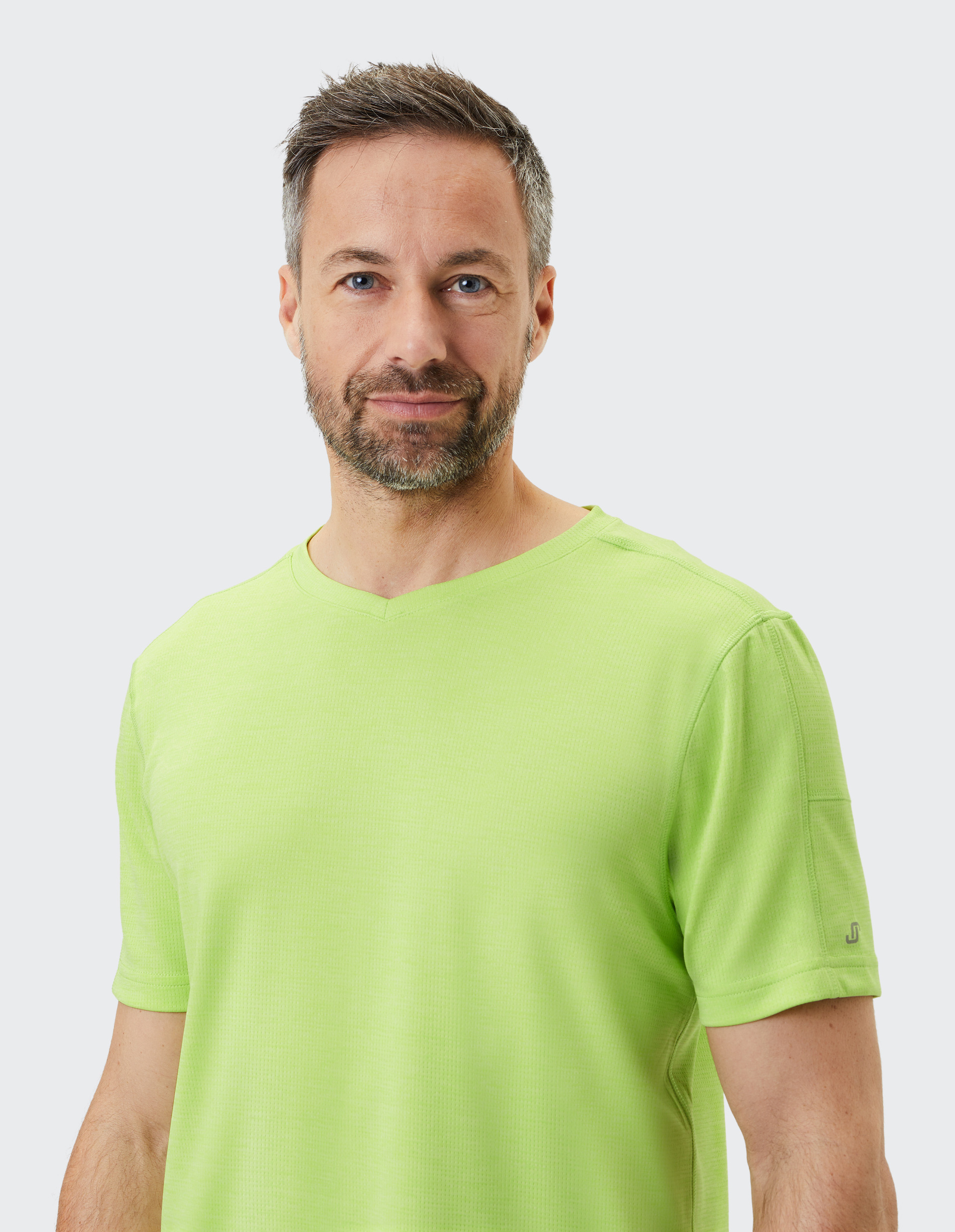 Mann mit kurzem Haar und Bart trägt ein hellgrünes T-Shirt vor hellem Hintergrund und schaut freundlich in die Kamera.