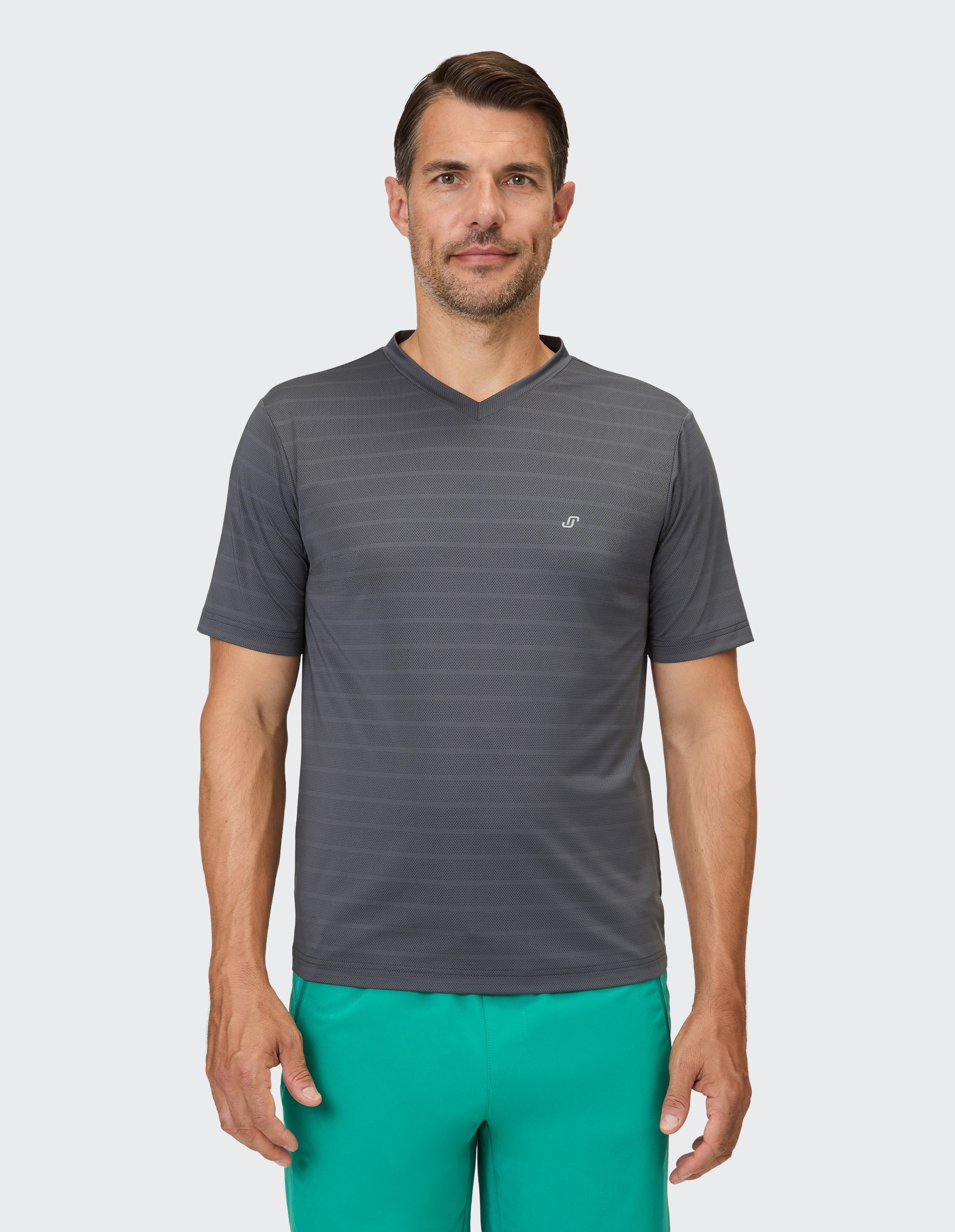 Ein Mann trägt ein dunkelgraues V-Shirt mit feinen horizontalen Streifen und türkisfarbene Shorts.