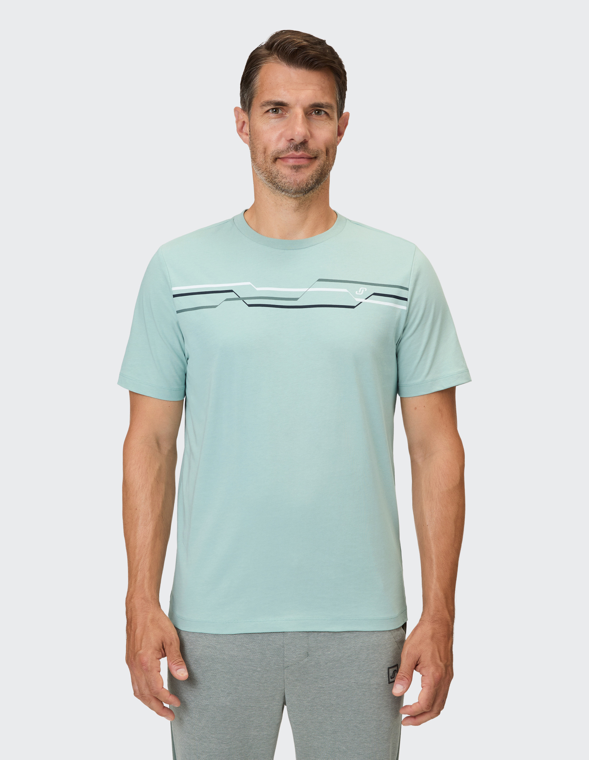 Hellgrünes T-Shirt mit geometrischen Streifen in Grau, Weiß und Dunkelblau auf der Brust.