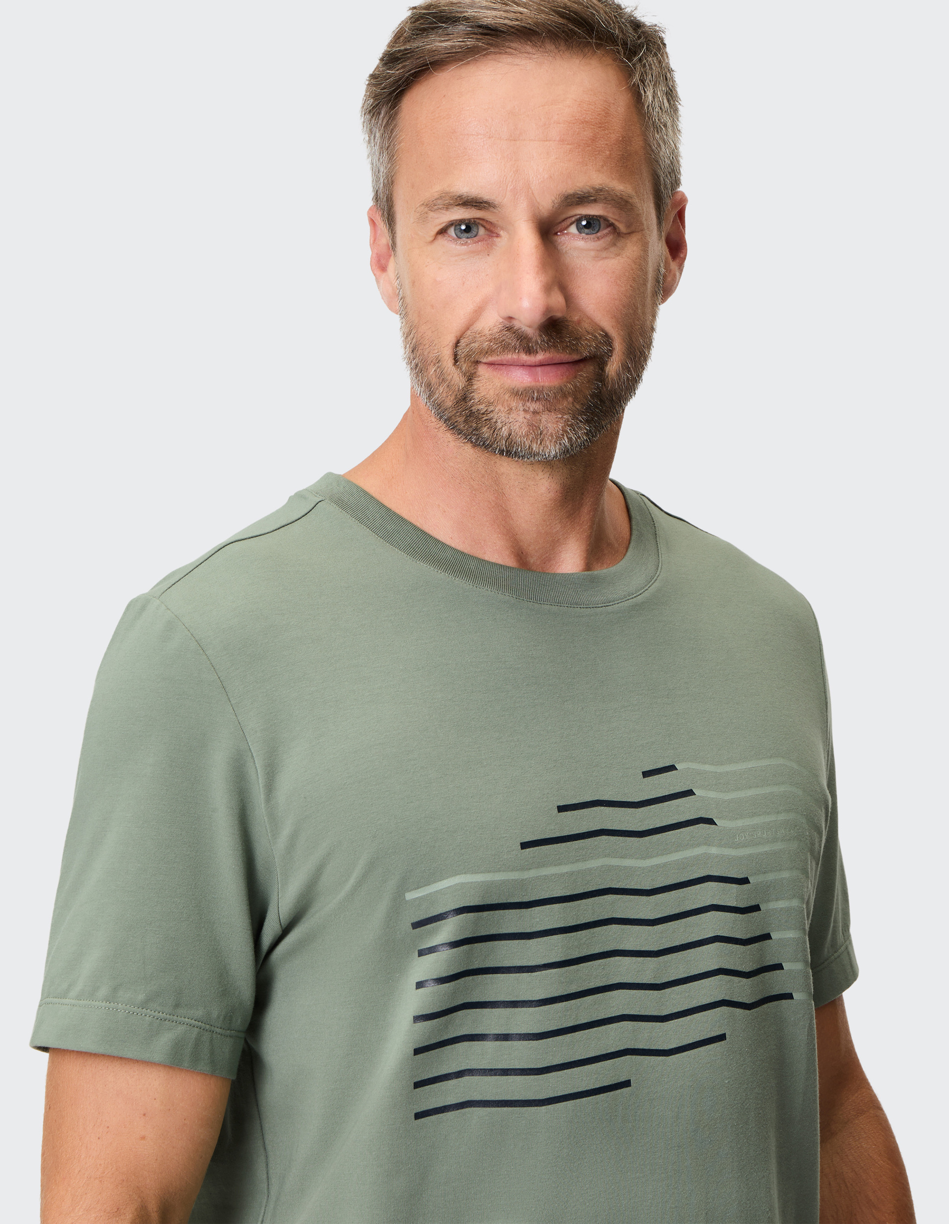 Olivgrünes T-Shirt mit Rundhalsausschnitt und stilisiertem, diagonalen Streifenmuster in Schwarz und Weiß auf der Vorderseite.