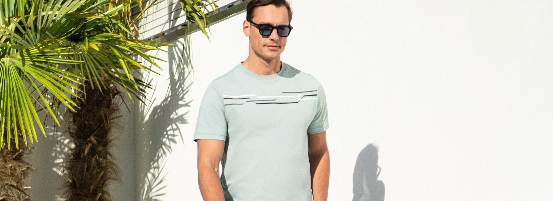 Mann in hellblauem Shirt und Sonnenbrille läuft.