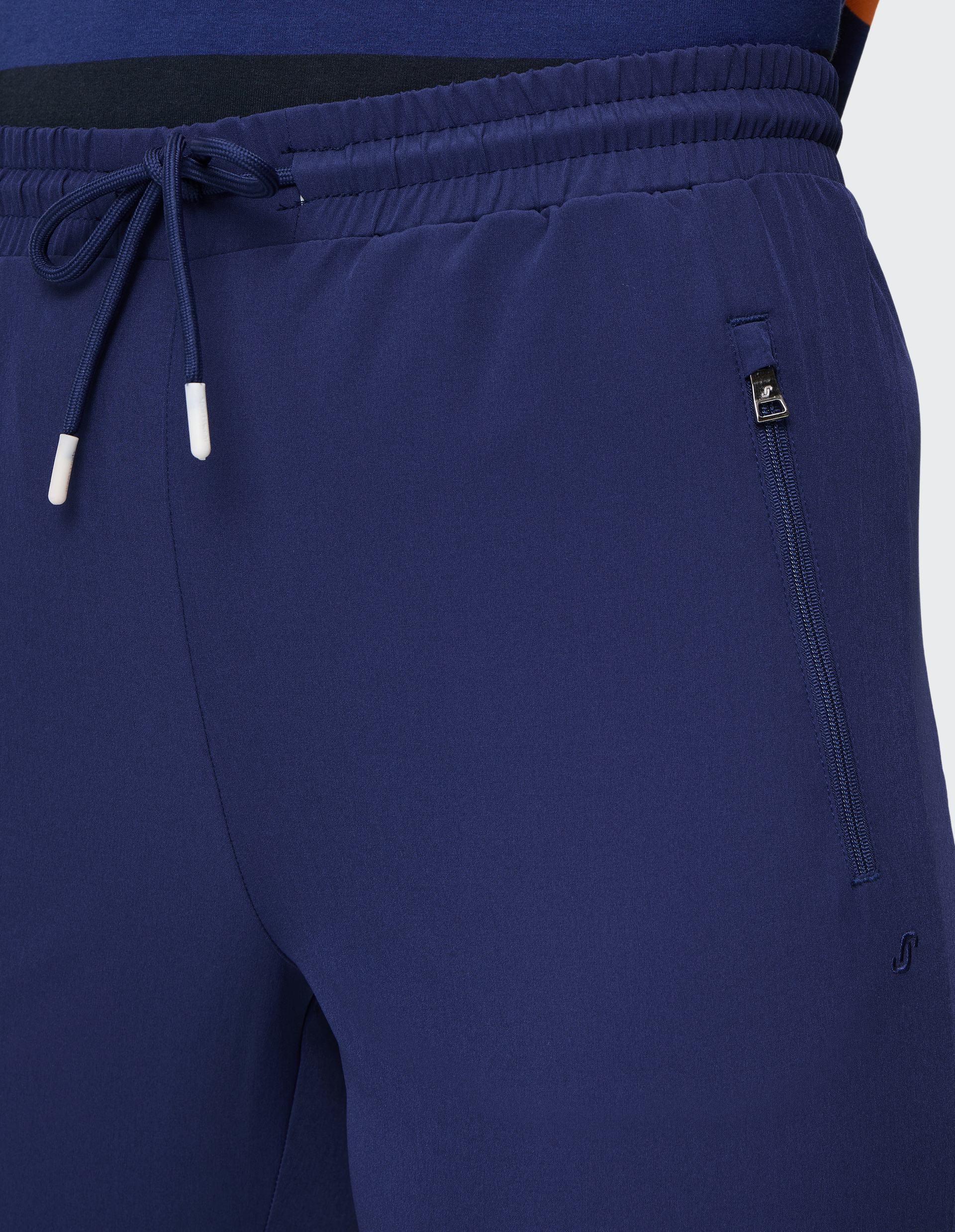 Dunkelblaue, knöchellange Jogginghose mit elastischem Bund und Kordelzug; seitliche Reißverschlusstaschen; schlichte Optik.