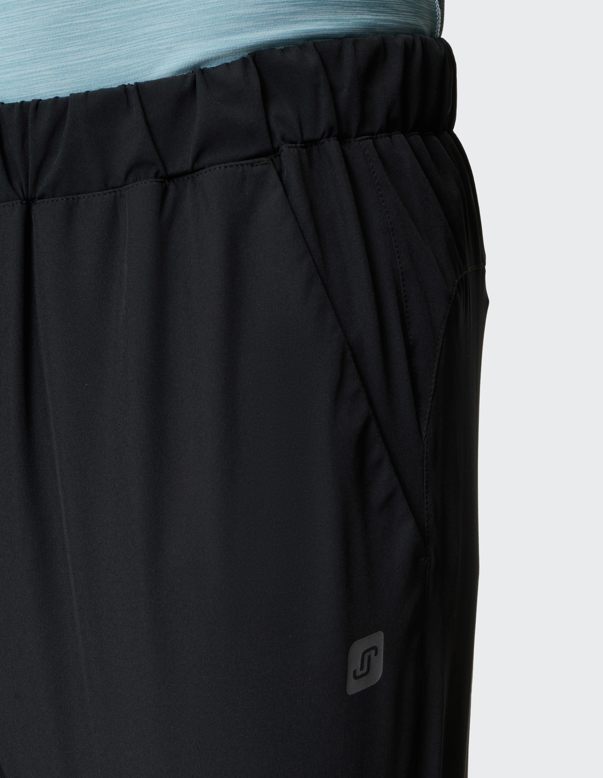 Schwarze Sporthose mit elastischem Bund und Seitentasche am Träger eines blau gestreiften Oberteils, Logo am unteren Bein.