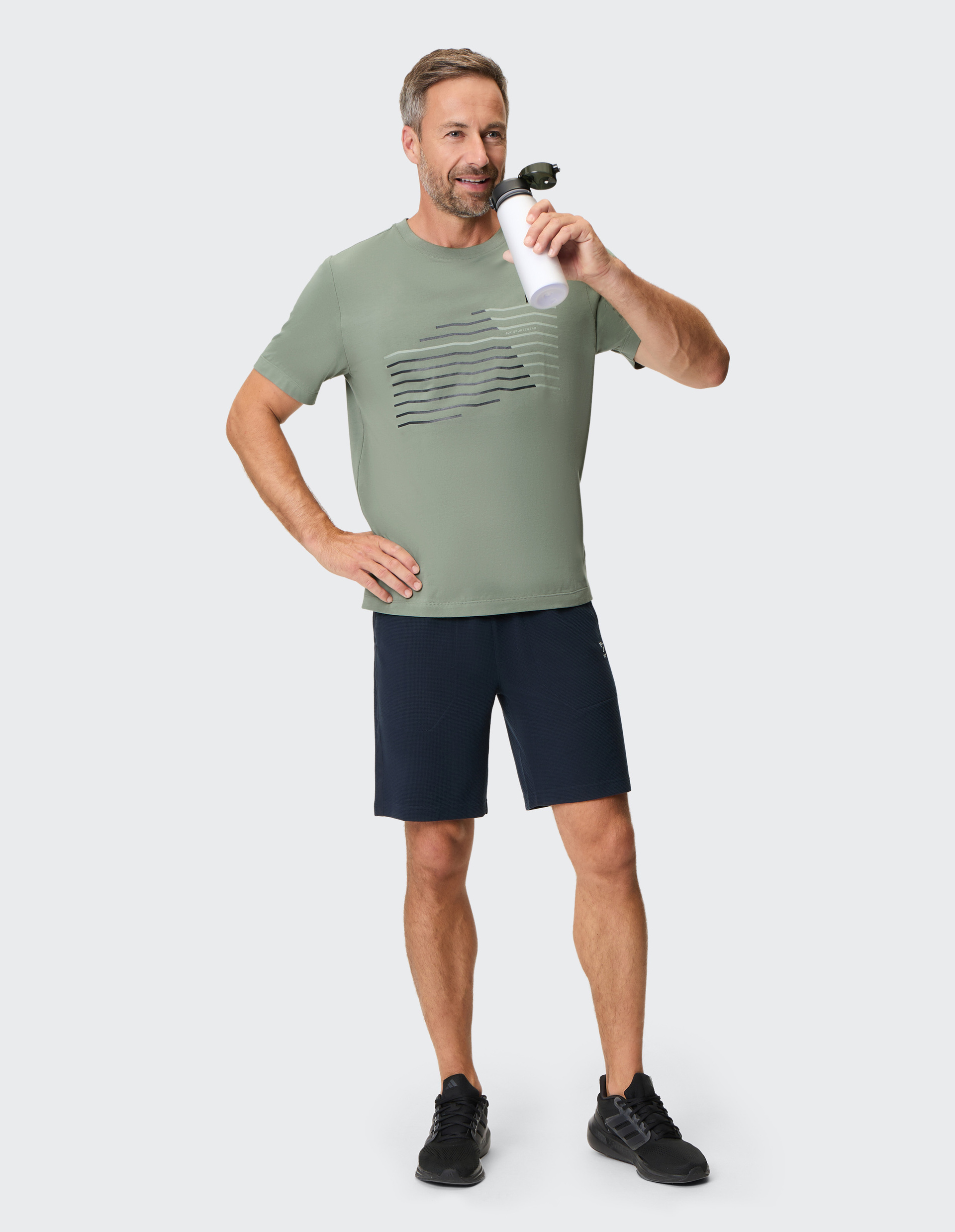 Olivgrünes T-Shirt mit Rundhalsausschnitt und stilisiertem, diagonalen Streifenmuster in Schwarz und Weiß auf der Vorderseite.