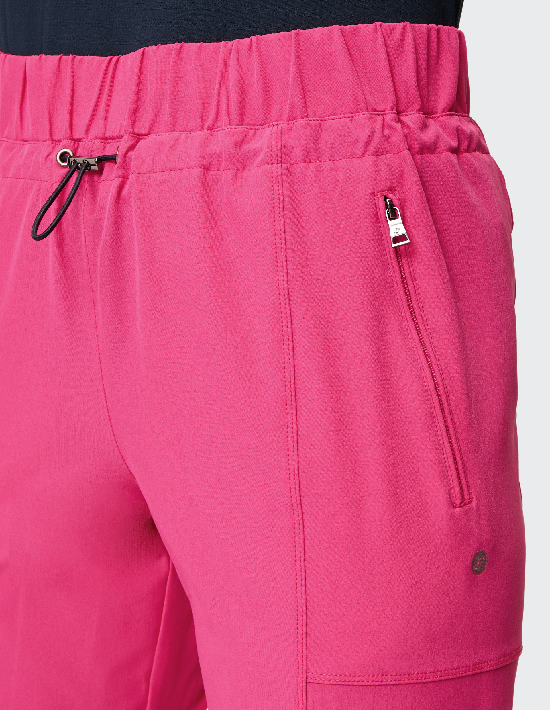 Eine pinke Sporthose mit elastischem Bund und Kordelzug, seitlicher Reißverschlusstasche und dezenter Logostickerei in der Nähe.