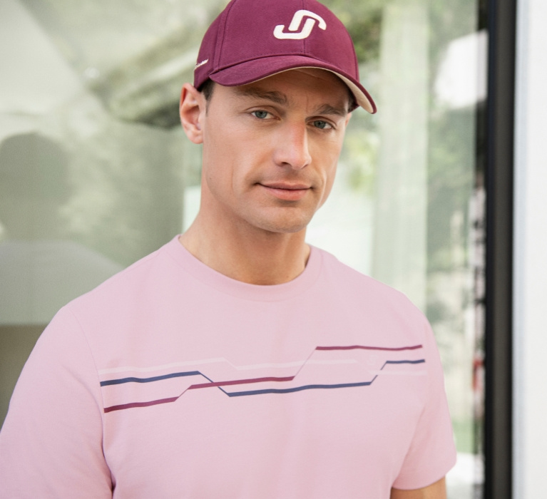 Mann mit rosa Shirt und Cap der Marke JOY sportswear.