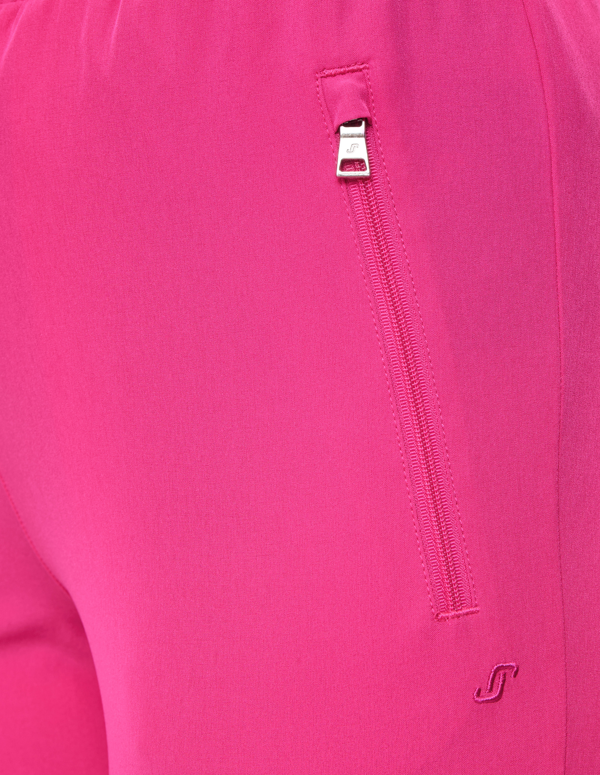 Nahaufnahme einer pinken Sporthose mit einem Reißverschluss an der Tasche und einem kleinen, gestickten Logo darunter.