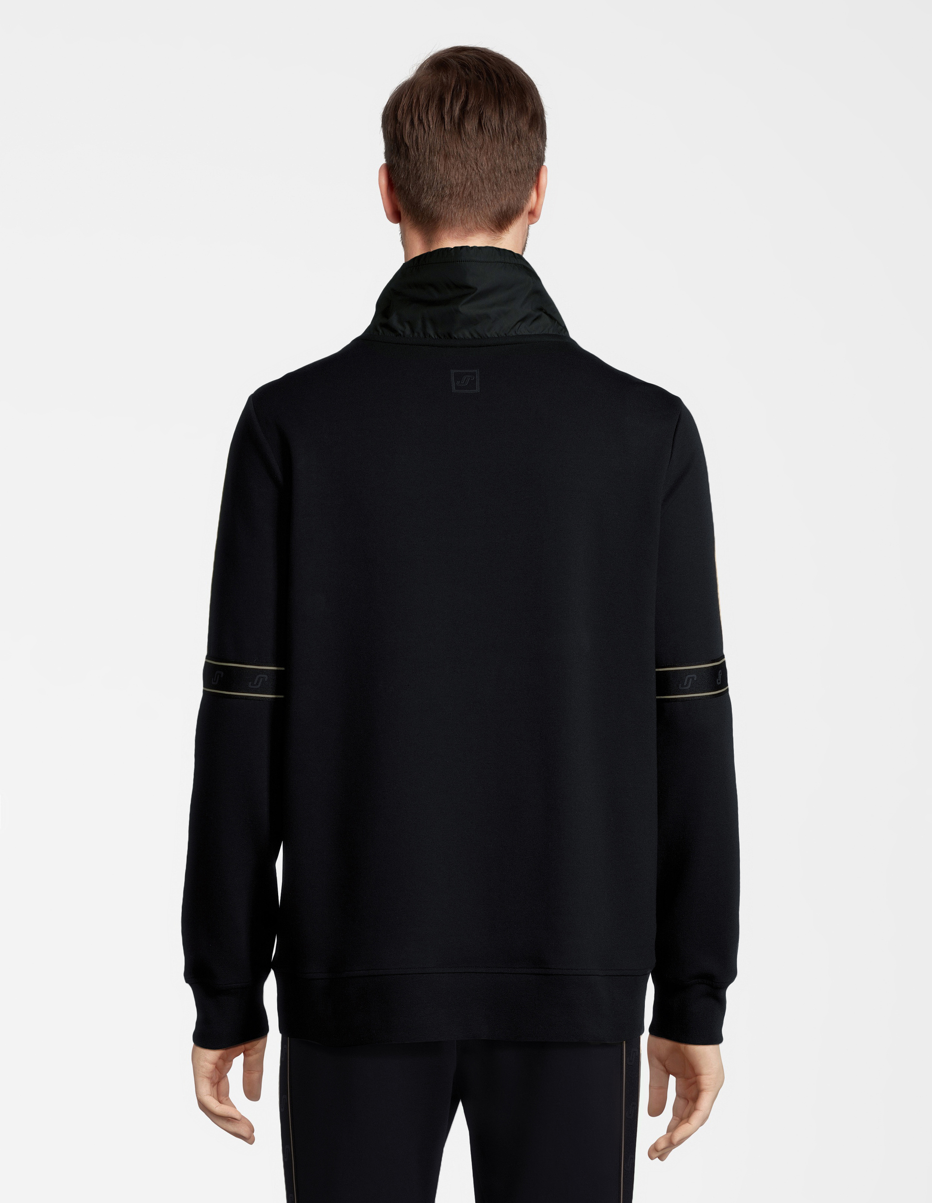 Rückansicht einer Person in schwarzem Pullover mit hohem Kragen und dekorativem Streifen auf den Ärmeln, auf weißem Hintergrund.