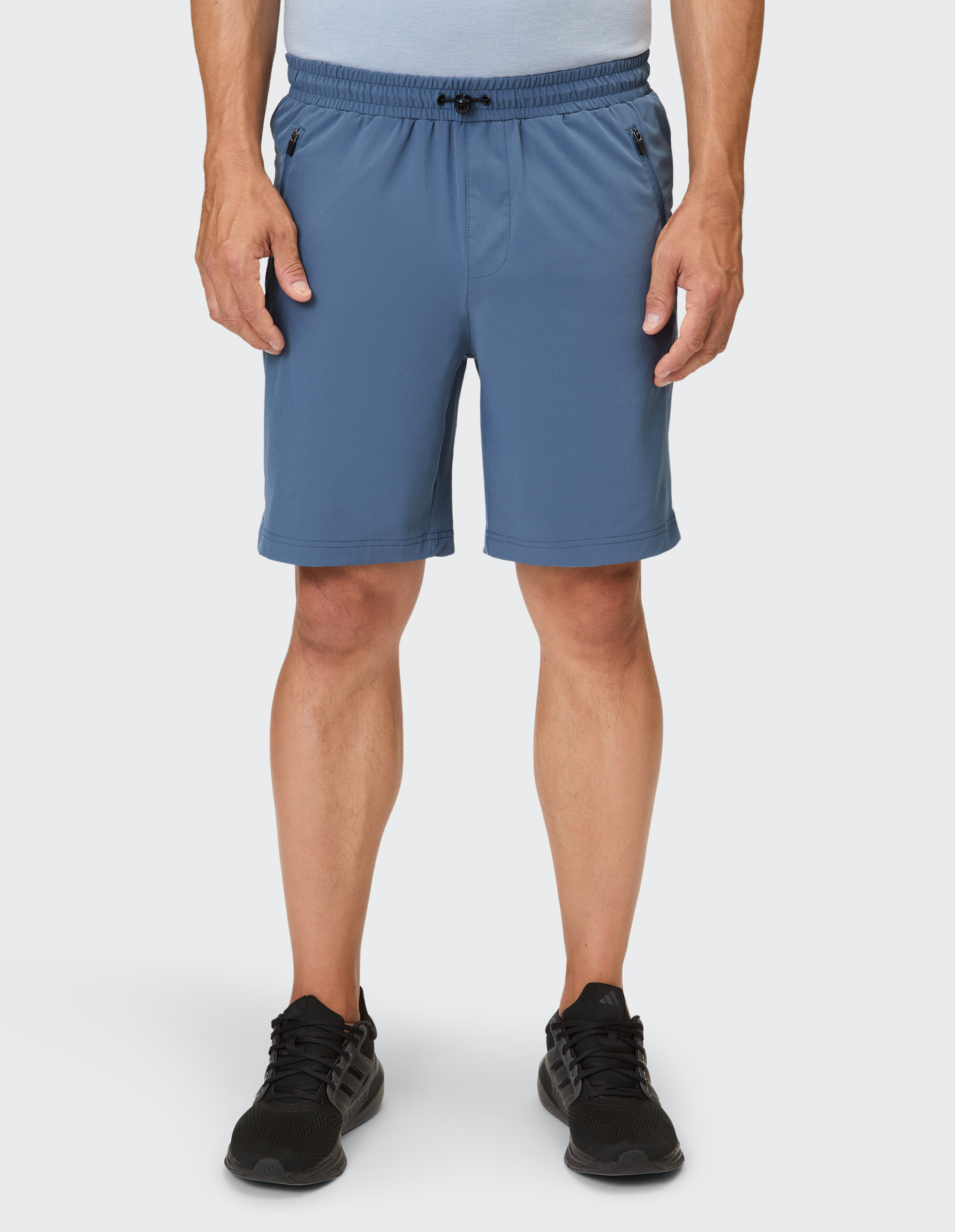 Ein Mann trägt eine blaue, lockere Shorts mit Kordelzug und Reißverschlusstaschen.