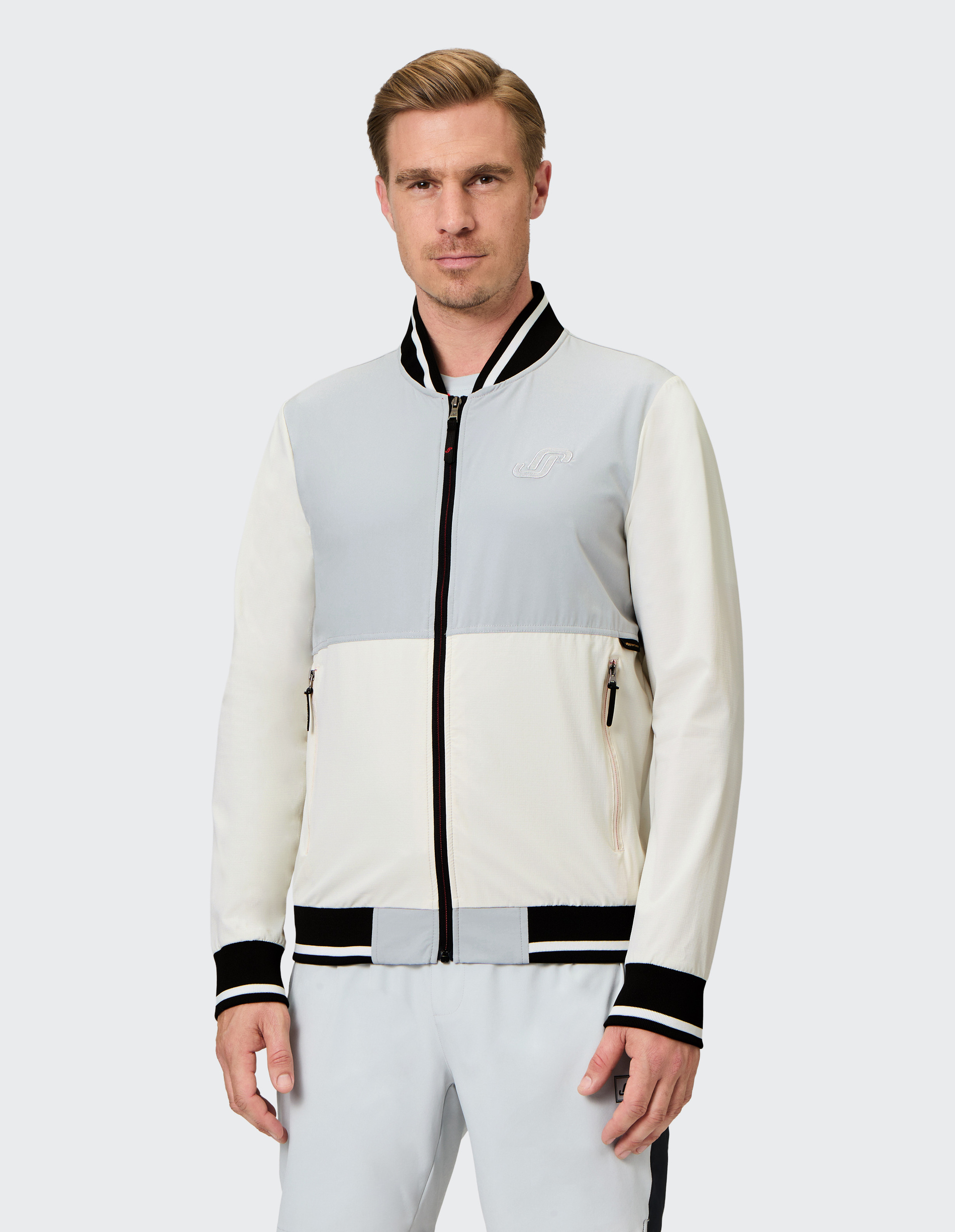 Weiße und graue Jacke mit schwarzem Kragen und Bündchen, Reißverschluss vorne, seitliche Taschen, Logo-Emblem auf der Brust.