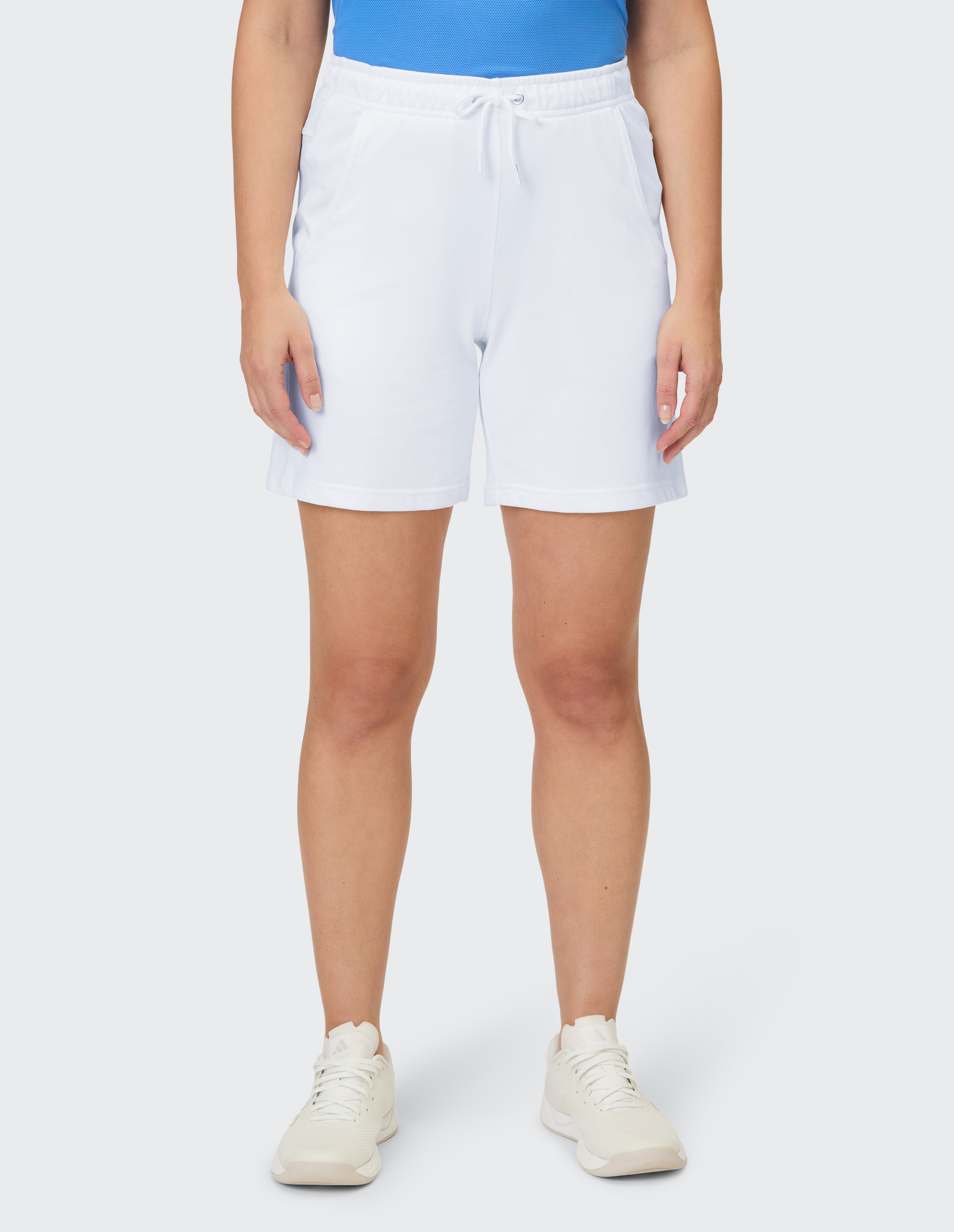Eine Frau trägt weiße Trainingsshorts mit einem Kordelzugbund und passende Laufschuhe.