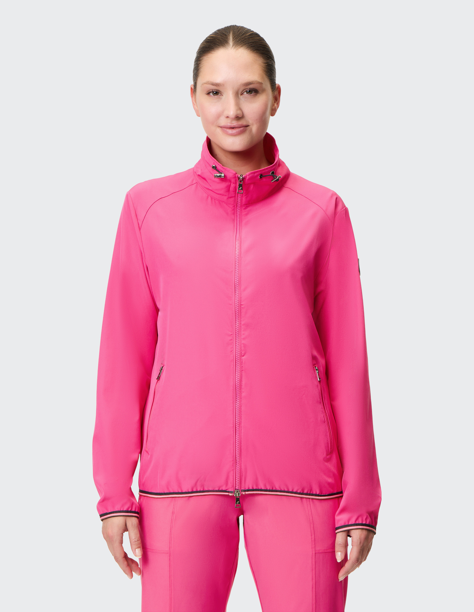 Eine leuchtend pinke Damenjacke mit durchgehendem Reißverschluss, hohem Kragen und seitlichen Reißverschlusstaschen.