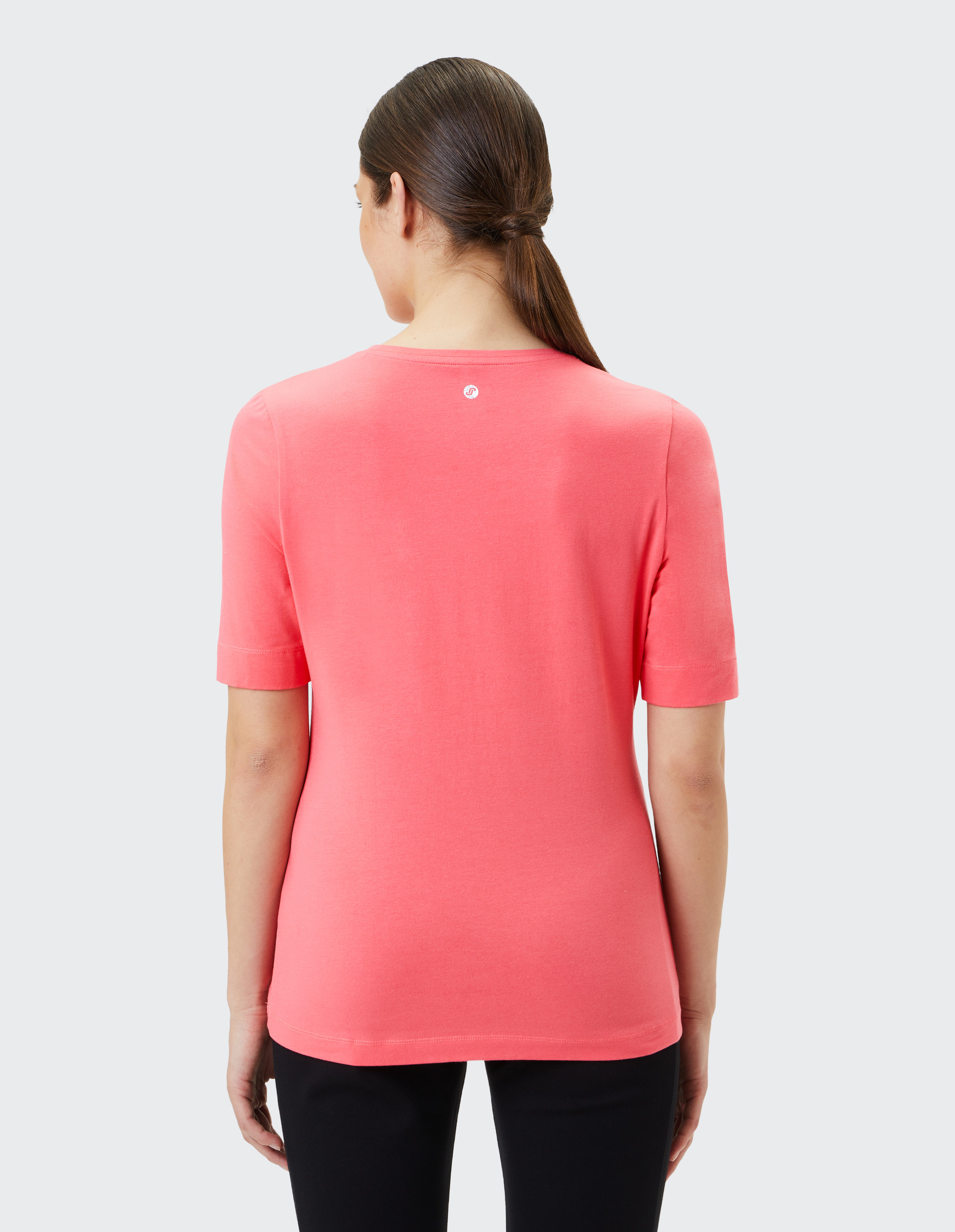 Koralrotes T-Shirt mit rundem Kragen, kurzen Ärmeln und eingeprägtem Schriftzug \\\\\\\\\\\\\\\\\\\\\\\\\\\\\\\"JOY IS NOW\\\\\\\\\\\\\\\\\\\\\\\\\\\\\\\" auf der Vorderseite.