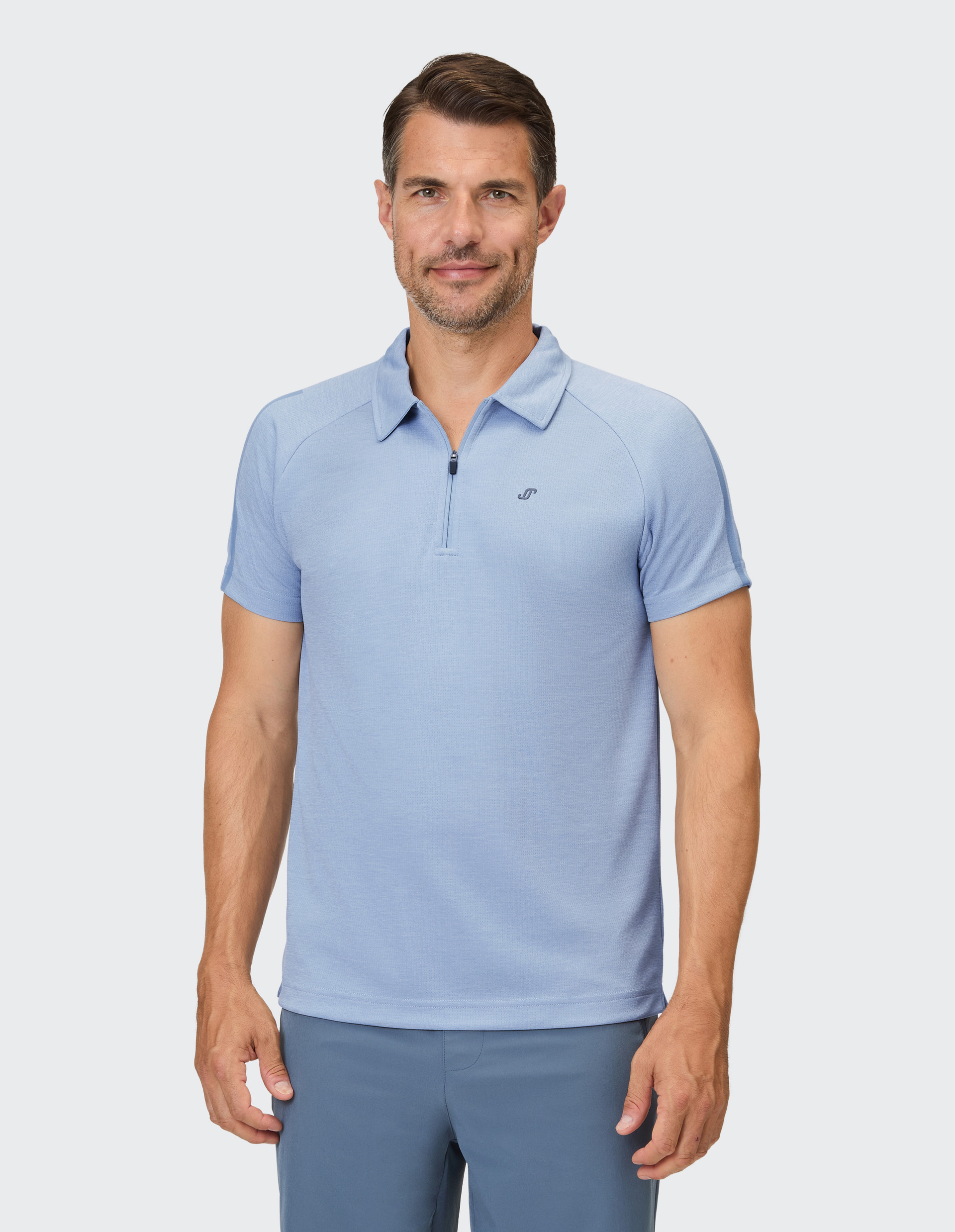 Ein Mann trägt ein hellblaues Poloshirt mit Reißverschluss und dazu passende blaue Hosen.
