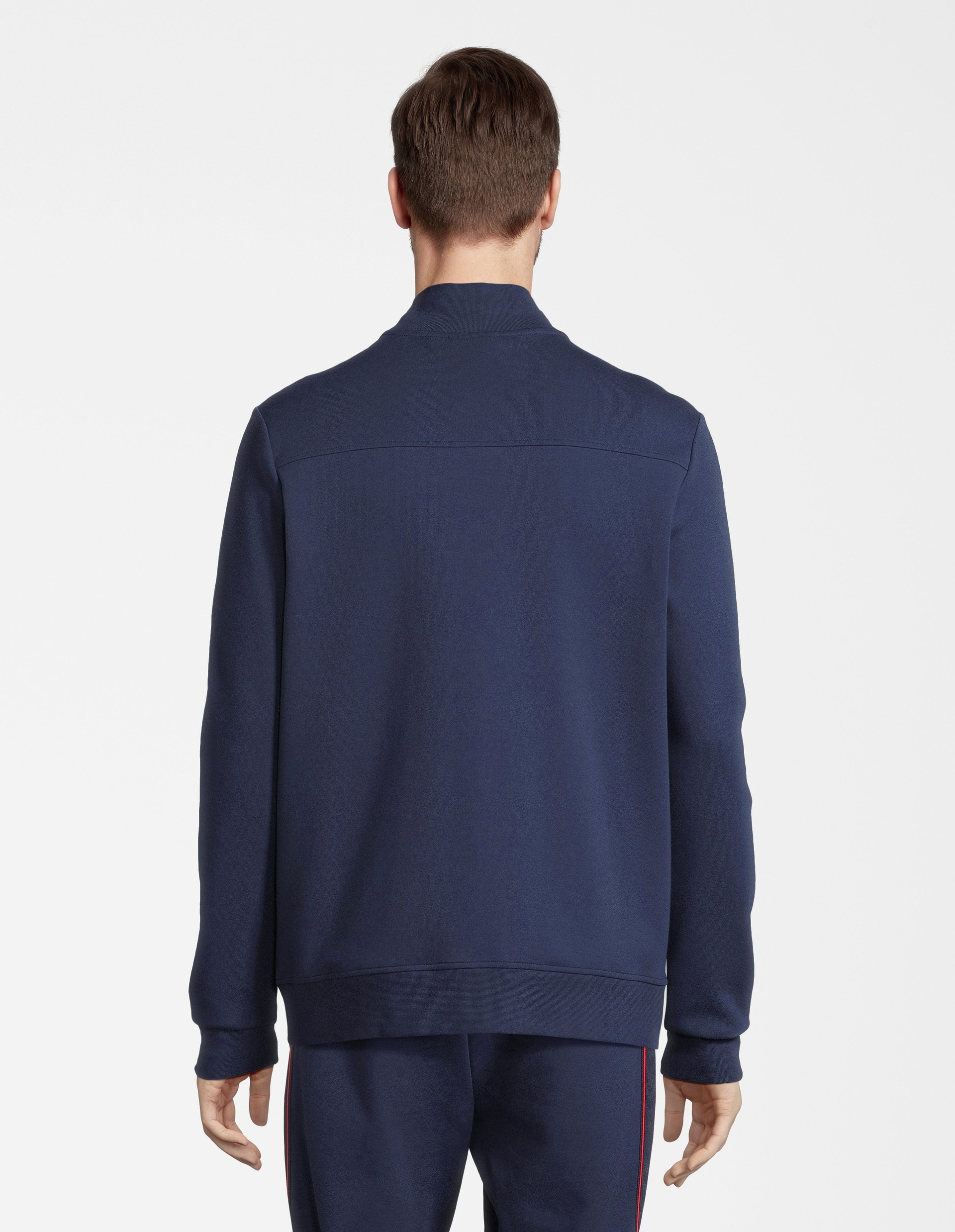 Dunkelblaue Jacke mit Reißverschluss, Stehkragen und einem dezenten roten Streifen über der Brust mit Logos verziert.