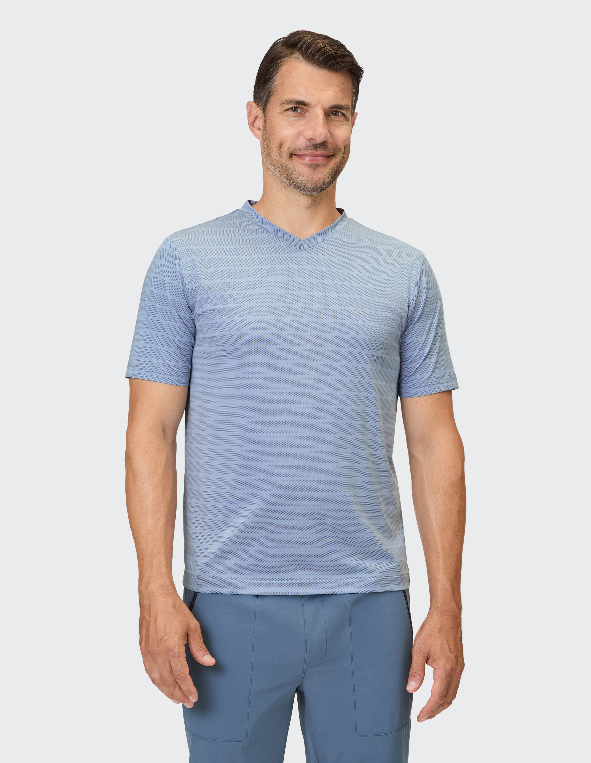 Ein Mann trägt ein hellblau gestreiftes Poloshirt mit V-Ausschnitt.