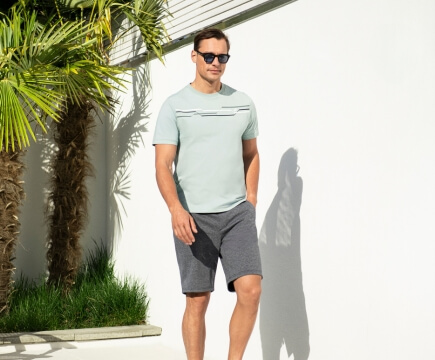 Mann mit sommerlichen Outfit und Sonnenbrille läuft auf die Kamera zu.